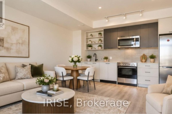 Open concept living space featuring a grey and white kitchen with stainless steel appliances and light wood flooring. - 714 - 2300 St. Clair Avenue W, Toronto