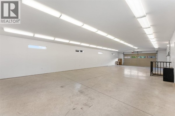 Wide view of the expansive garage interior with white walls, concrete floor, and an open garage door. - 714 Turner Road, Kelowna