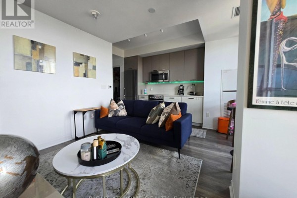 Compact kitchen with stainless steel appliances, white countertops, and beige cabinets. - 715 - 2301 Danforth Avenue, Toronto