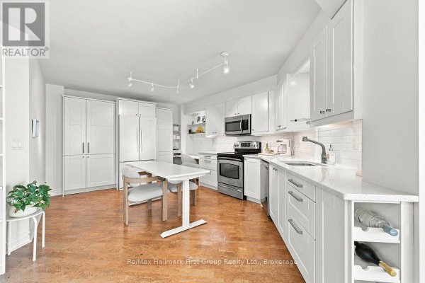 White kitchen with stainless steel appliances, quartz countertops, and a small dining table. - 715 - 340 Watson Street W, Whitby