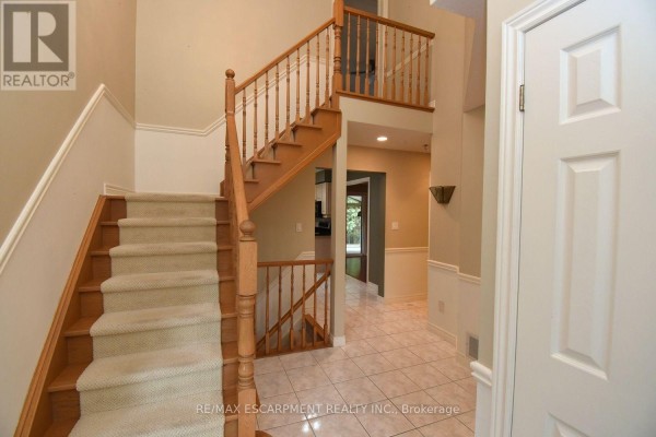 Looking down from the top of the stairs into the foyer with a double front door and tile floors. - 715 Bateman Court, Burlington