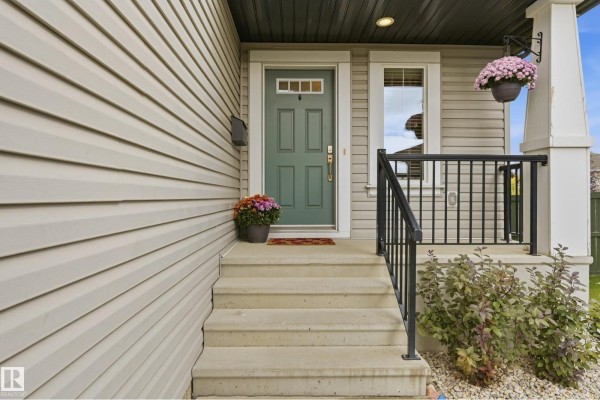 Close-up of the front entrance steps, green door, and porch railing. - 715 Cache Pl, Sherwood Park