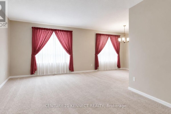Living room with beige walls, plush carpet, and two large windows with white sheers and red drapes. - 715 Waverly Street N, Oshawa