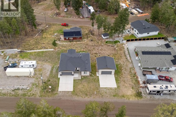 Aerial view of the property at 7151 Dunwaters Road, Kelowna, showing the house, detached garage, and surrounding landscape. - 7151 Dunwaters Road, Kelowna