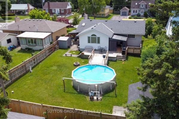 Backyard view of a house with an above-ground pool, wooden deck, and grassy lawn. - 716 Monsarrat Avenue, London East