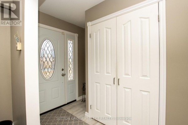 Interior entryway with a white front door with a decorative glass oval and double closet doors. - 716 Monsarrat Avenue, London East