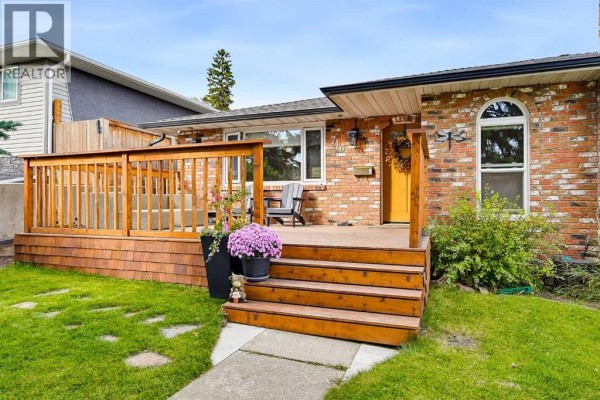 Close-up front view of a brick house, showcasing the wooden deck, steps, and front door. - 716 Seymour Avenue Sw, Calgary