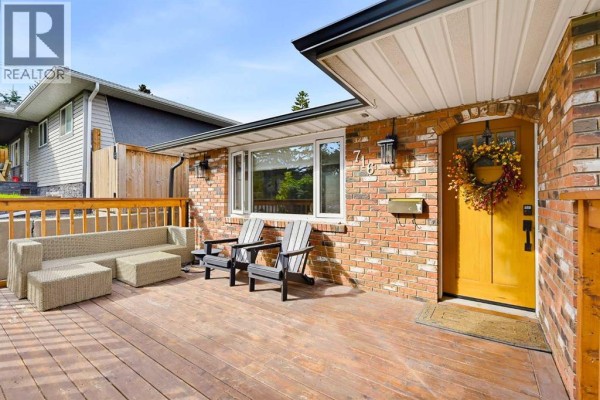 Exterior view of a wooden deck with patio furniture, adjacent to the brick house entrance. - 716 Seymour Avenue Sw, Calgary