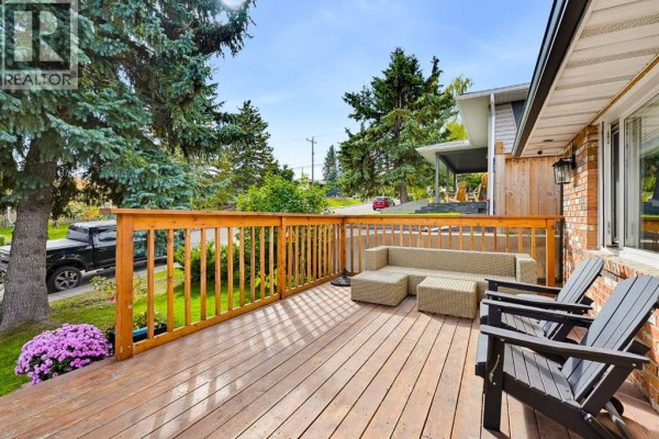 View from a wooden deck overlooking a street, with trees and neighboring houses visible. - 716 Seymour Avenue Sw, Calgary