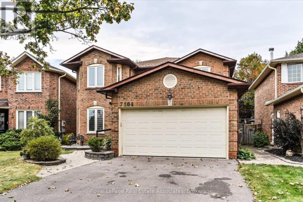 Side view of the house showing brick exterior, windows, and garage. - 7164 Danton Promenade, Mississauga