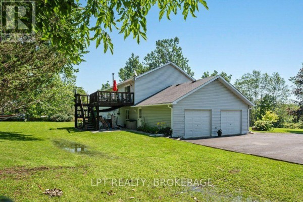 Aerial view of a property with a house, pool, driveway, garage, and surrounding trees and fields. - 717 County 14 Road, Stone Mills