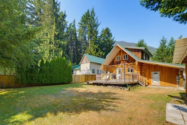 Two ATVs parked on the lawn in front of a log cabin with a large A-frame window. - 71788 Meadow Road, Sunshine Valley, Sunshine Valley