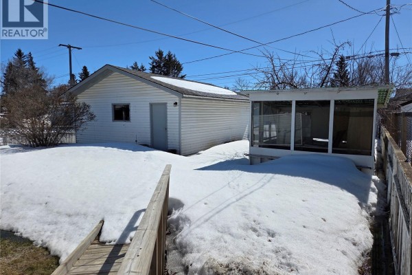 Dining area with a window overlooking trees and an opening to a living area. - 718 98th Avenue, Tisdale