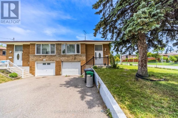 Front view of a brick house with stone accents, showing two garage doors and a lawn. - 7187 Darcel Avenue, Mississauga