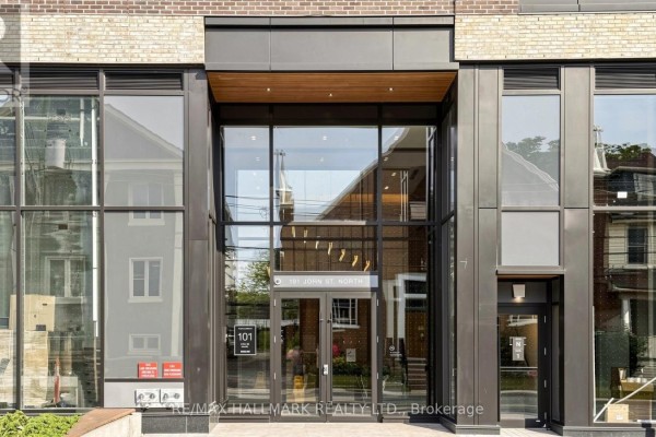 Front entrance of a modern apartment building with large glass doors and metal framing. - 719 - 101 John Street N, Hamilton