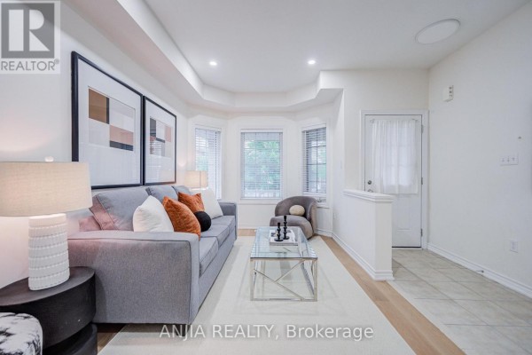 Living room with grey sofa, glass coffee table, and bay windows. - 719 Hammersly Boulevard, Markham