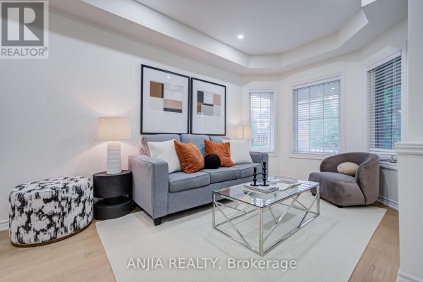 Living room with gray sofa, accent chairs, ottoman, and geometric artwork. - 719 Hammersly Boulevard, Markham