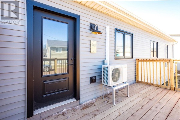 Front door of the townhouse with a glass panel and a numbered plaque on grey siding. - 71b Woodleigh Drive, Kensington
