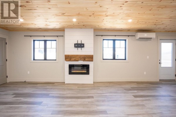 Living room with light grey flooring, a modern fireplace, and two windows under a wood-paneled ceiling. - 71b Woodleigh Drive, Kensington