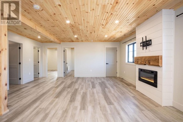 Living room with multiple doorways, light grey flooring, a fireplace, and a wood-paneled ceiling. - 71b Woodleigh Drive, Kensington