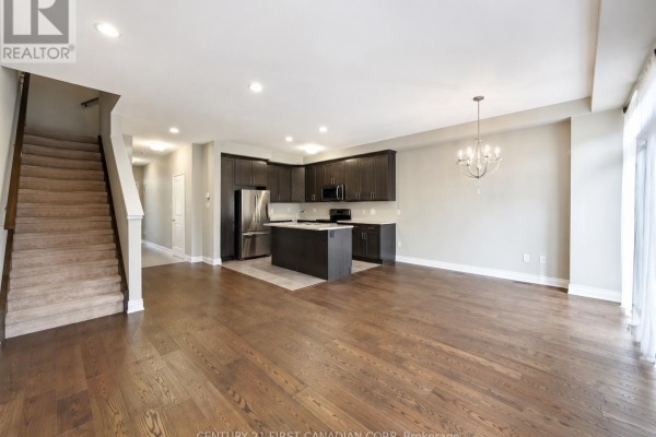 Open concept living area with hardwood floors, dark cabinets, and kitchen island. - 72 - 2070 Meadowgate Boulevard, London South
