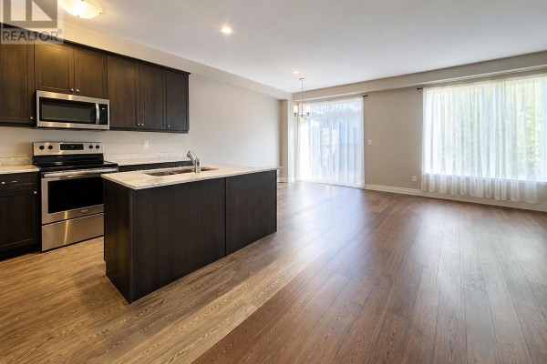 Kitchen with dark wood cabinets, stainless steel appliances, and island with granite countertop. - 72 - 2070 Meadowgate Boulevard, London South
