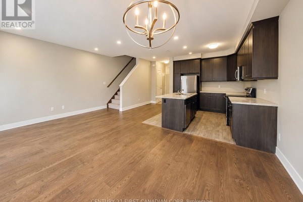 Living and kitchen area with hardwood floors, dark cabinets, and central island. - 72 - 2070 Meadowgate Boulevard, London South