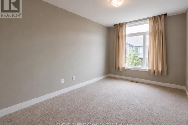 Bedroom with beige carpet, large window, and beige curtains. - 72 - 2070 Meadowgate Boulevard, London South