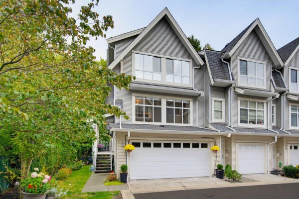 Exterior of a grey townhouse with a white garage door and large windows. - 72 6450 199 Street, Langley