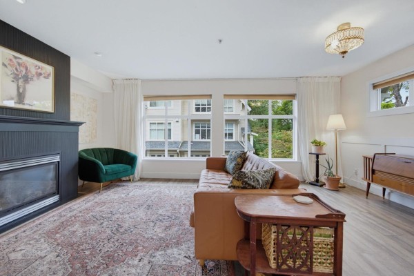 Living room with a fireplace, leather sofa, large windows, and a patterned rug. - 72 6450 199 Street, Langley