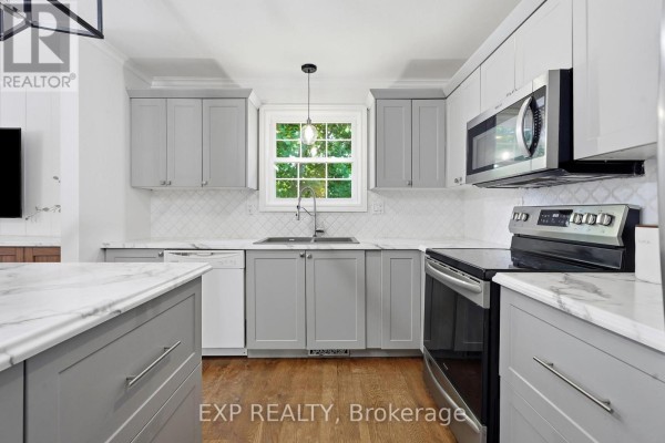 Modern kitchen with gray cabinets, marble counters, stainless steel appliances, and island - 72 Crestlynn Crescent Norfolk