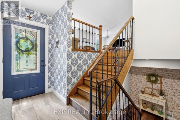 Foyer with a blue front door, patterned wallpaper, and a wooden staircase with black metal spindles. - 72 Crestlynn Crescent, Norfolk