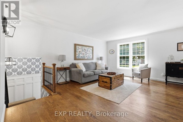 Living room with gray sofa, wooden trunk coffee table, hardwood floors, and large window - 72 Crestlynn Crescent Norfolk