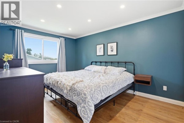 Bedroom with teal walls, metal bed frame, and hardwood floors - 72 Crestlynn Crescent Simcoe