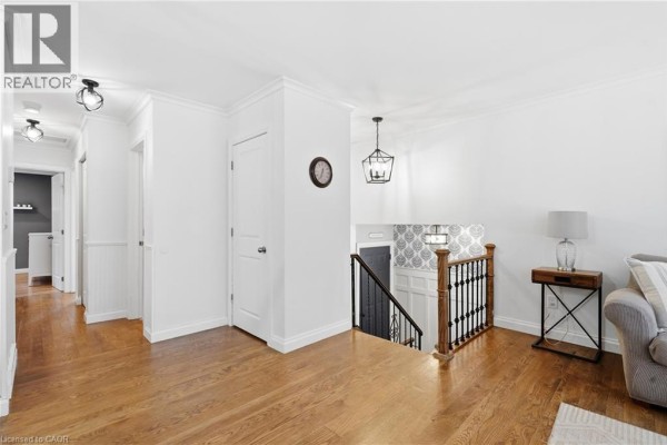 Upper hallway and landing with hardwood floors, white walls, and a staircase with wooden banister. - 72 Crestlynn Crescent, Simcoe