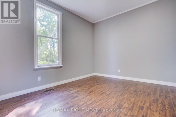 Empty room with grey walls, wood-look laminate flooring, and a tall window on the left. - 72 Dunedin Street, Orillia