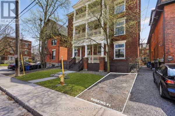 Gravel parking area marked Parking #1 beside a red brick building. - 72 Fifth Avenue, Ottawa