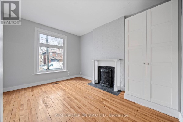 Room with light gray walls, white trim, a fireplace, and a large white wardrobe. - 72 Fifth Avenue, Ottawa