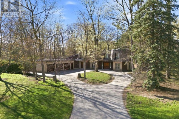 Exterior view of a brick and wood-sided house with a multi-stall garage and mature trees. - 72 Golf Avenue, Vaughan