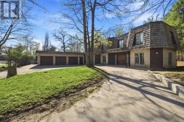 Front facade of a house with stone and wood siding, a large garage, and a paved driveway. - 72 Golf Avenue, Vaughan