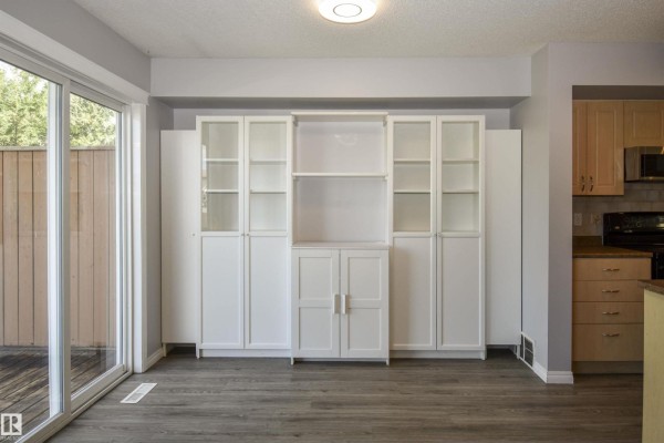 Living area with white built-in shelving units and dark wood flooring next to patio doors. - 72 Hartwick Ld, Spruce Grove