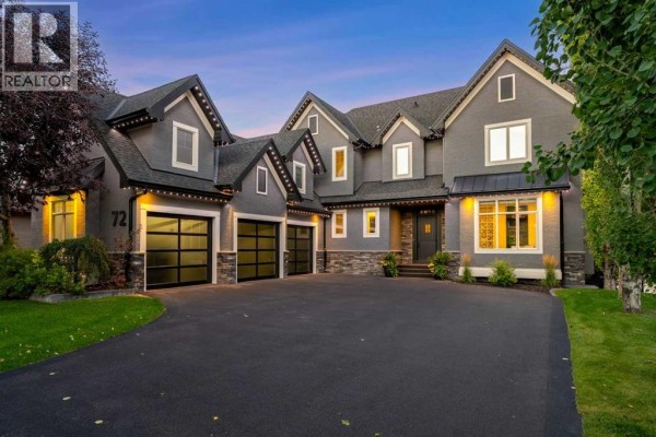 Front exterior of a large grey home with a dark roof, stone accents, and a paved driveway. - 72 Heritage Lake Shores, Heritage Pointe