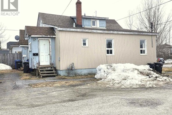 Living area with a chair, dining table, and large windows - 72 Lebel Avenue, Kirkland Lake