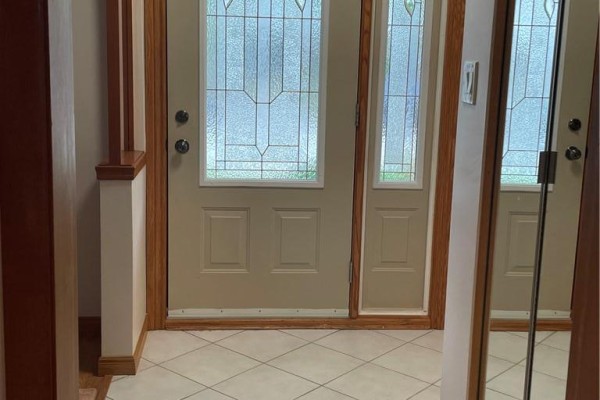 Interior entrance foyer with beige door, frosted glass panels, wood trim, and tiled floor. - 72 Purnell Drive, Hamilton