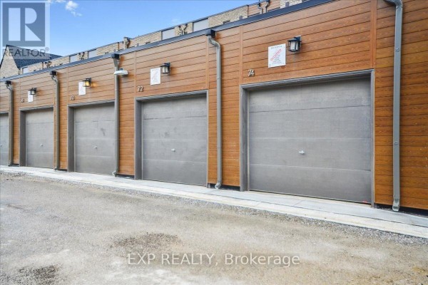 Exterior view of attached garages with numbered doors and wood-paneled siding. - 72 Turtle Island Road, Toronto