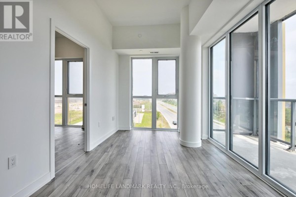 Spacious living room with light grey wood-look flooring, large windows, and a balcony door. - 720 - 1005 Dundas Street E, Oakville