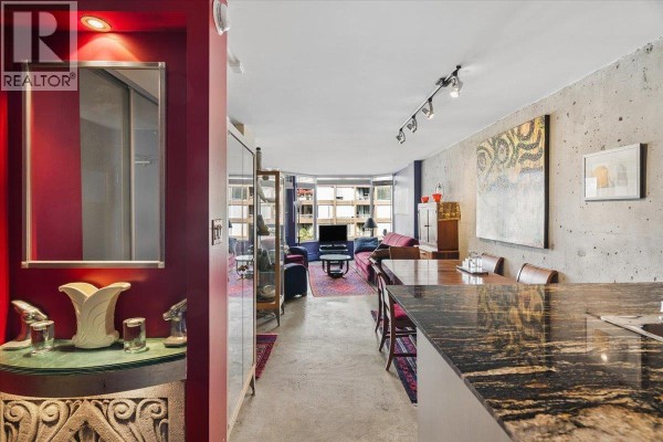 View from kitchen island into living and dining area with concrete walls and bay windows. - 720 1333 Hornby Street, Vancouver