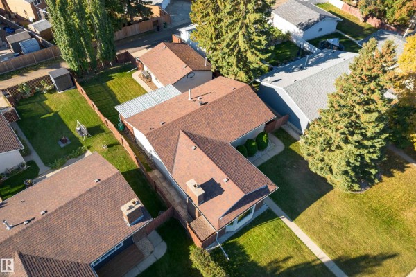 Aerial view of a beige bungalow with a brown roof, fenced yard, and mature trees. - 720 Knottwood Rd S Nw, Edmonton