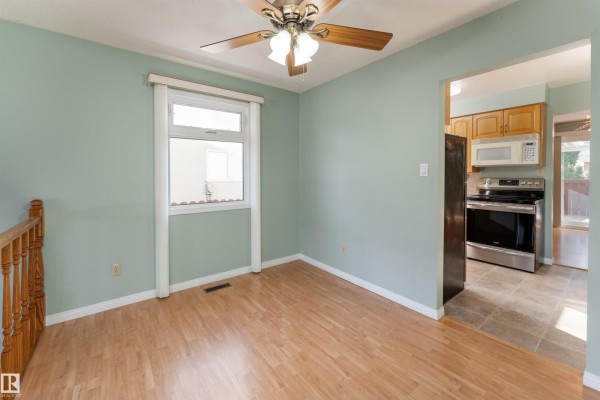 Interior room with light blue walls, wood laminate flooring, a ceiling fan, and a small window. - 720 Knottwood Rd S Nw, Edmonton