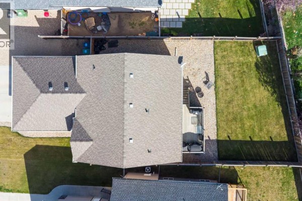 Aerial view of the backyard with a deck, green grass, and gravel. - 7207 39a Street, Lloydminster